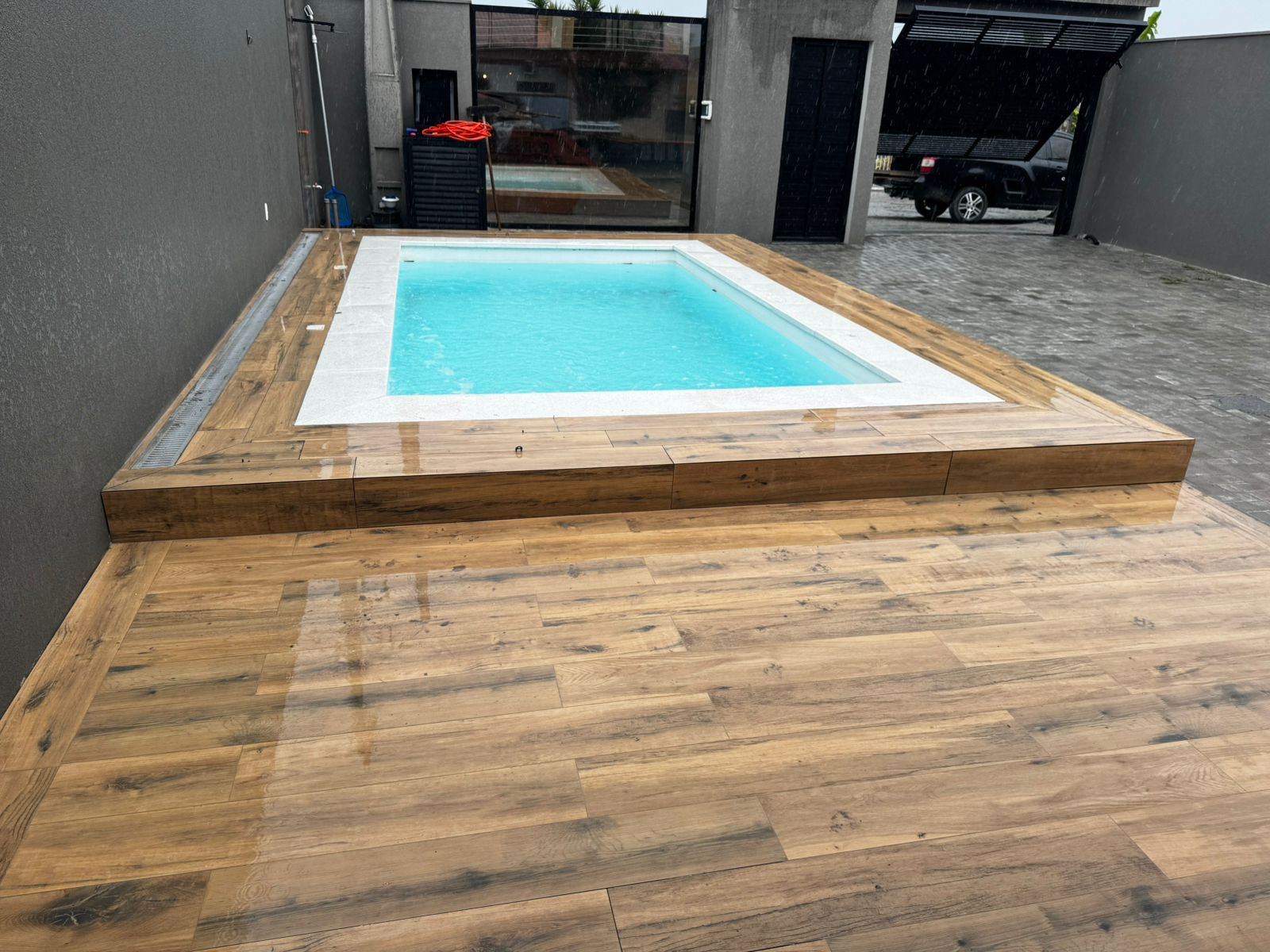 Área de lazer com piscina e deck em porcelanato amadeirado